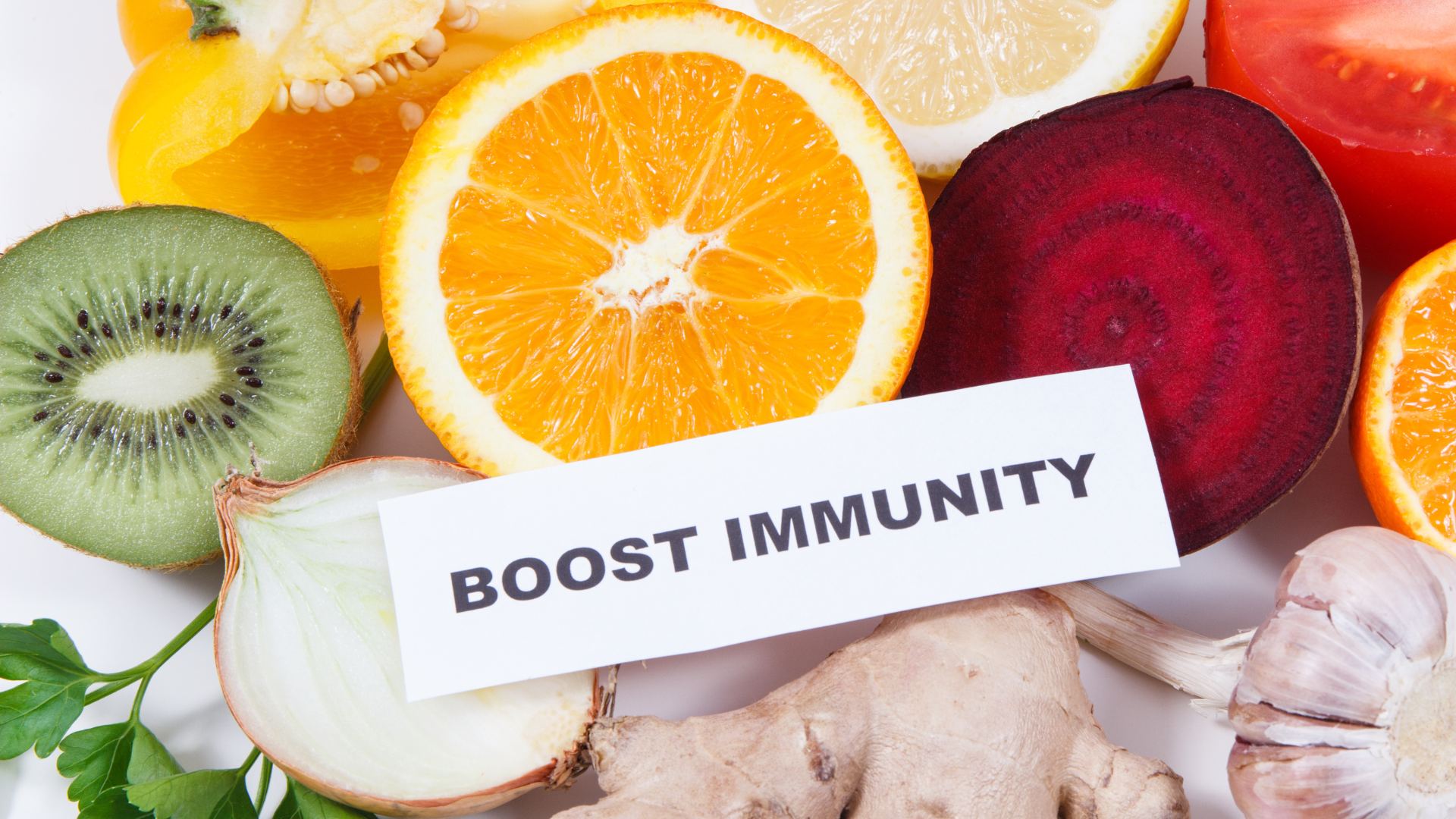 Buntes Obst und Gemüse – Orange, Kiwi, Rote Bete, Ingwer und Knoblauch – mit dem Schild „Boost Immunity“